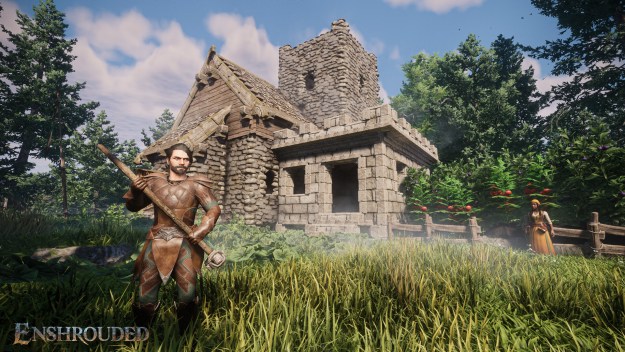 Man holding a tool in a garden in front of a house, with his wife standing in the background.